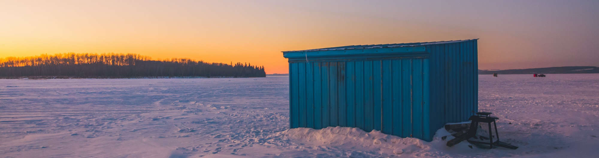 ice fishing hutson frozen lake by sunset